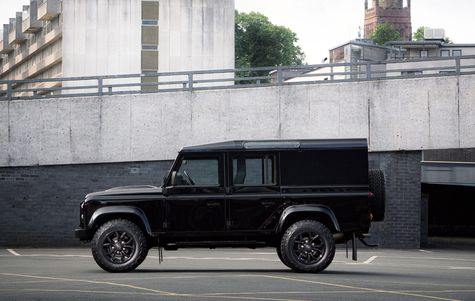 Black Land Rover Defender parked in an urban setting.
