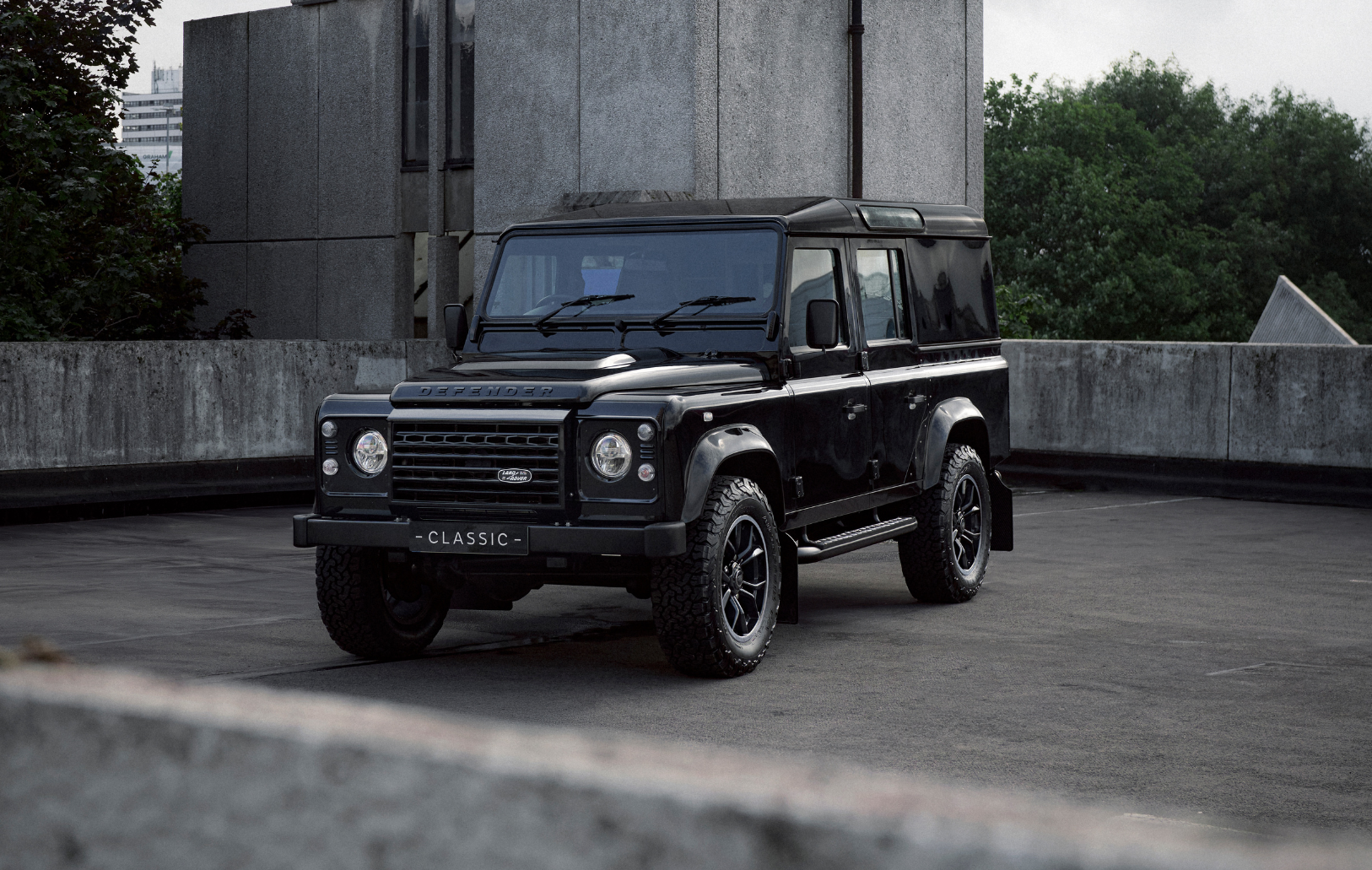 Black Land Rover Defender on a rooftop with 'CLASSIC' plate.