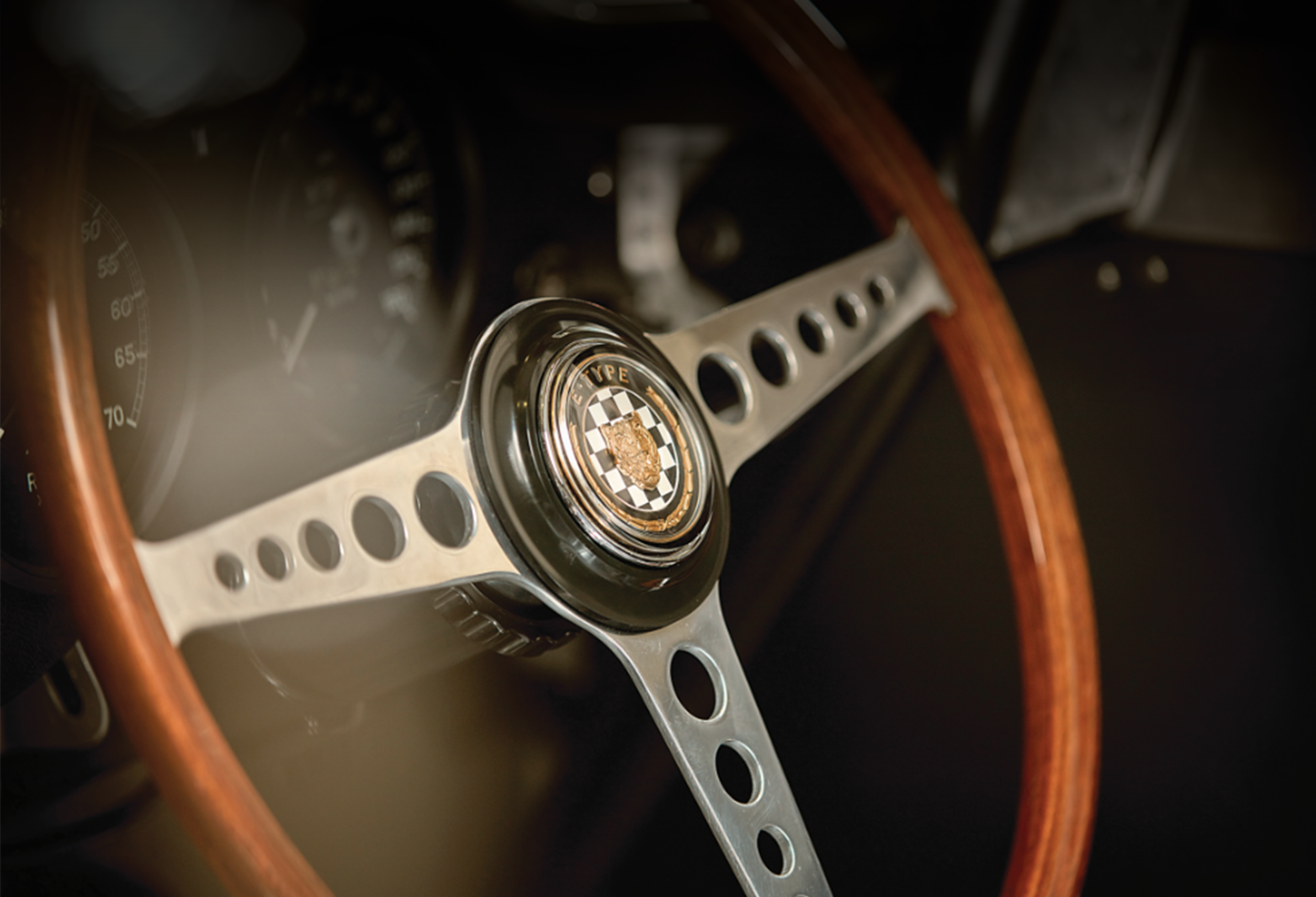 Classic car steering wheel with &ldquo;E-TYPE&rdquo; customised emblem.