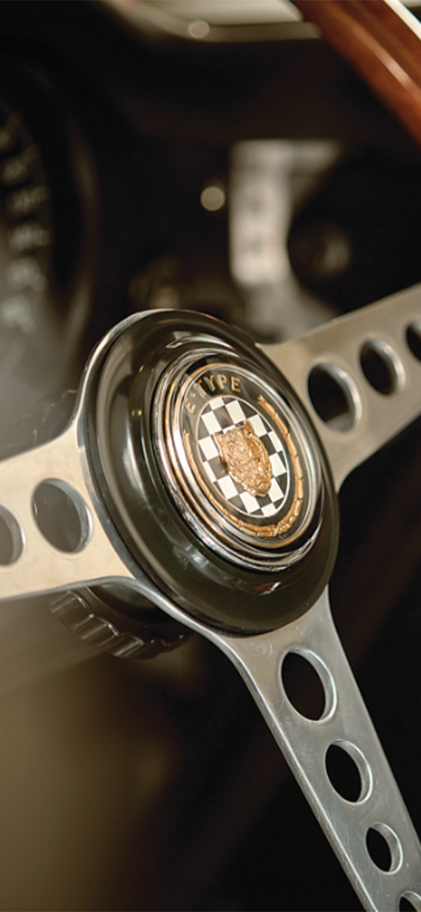 Classic car steering wheel with &ldquo;E-TYPE&rdquo; customised emblem.