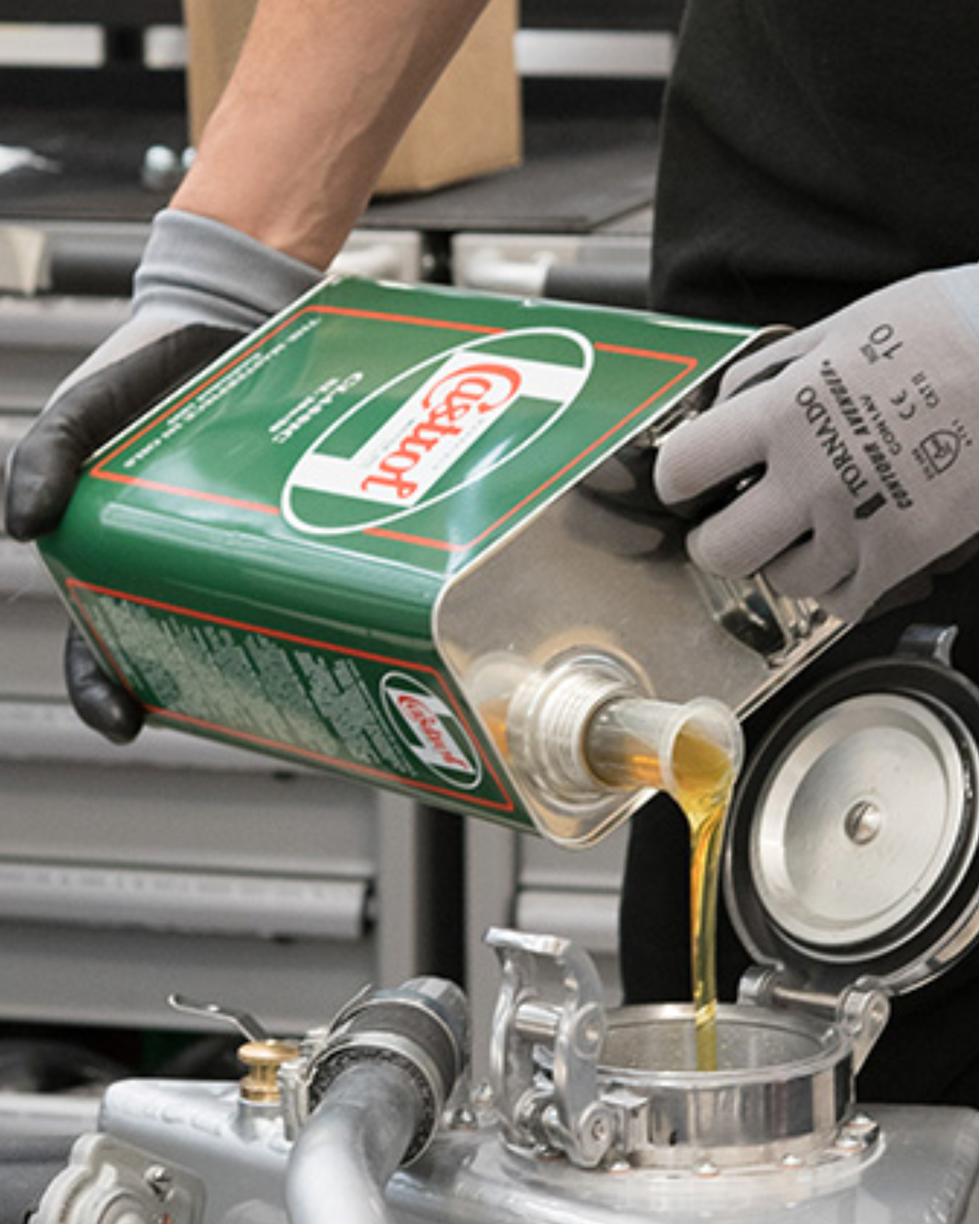 Person pouring oil from green Castrol container into engine.