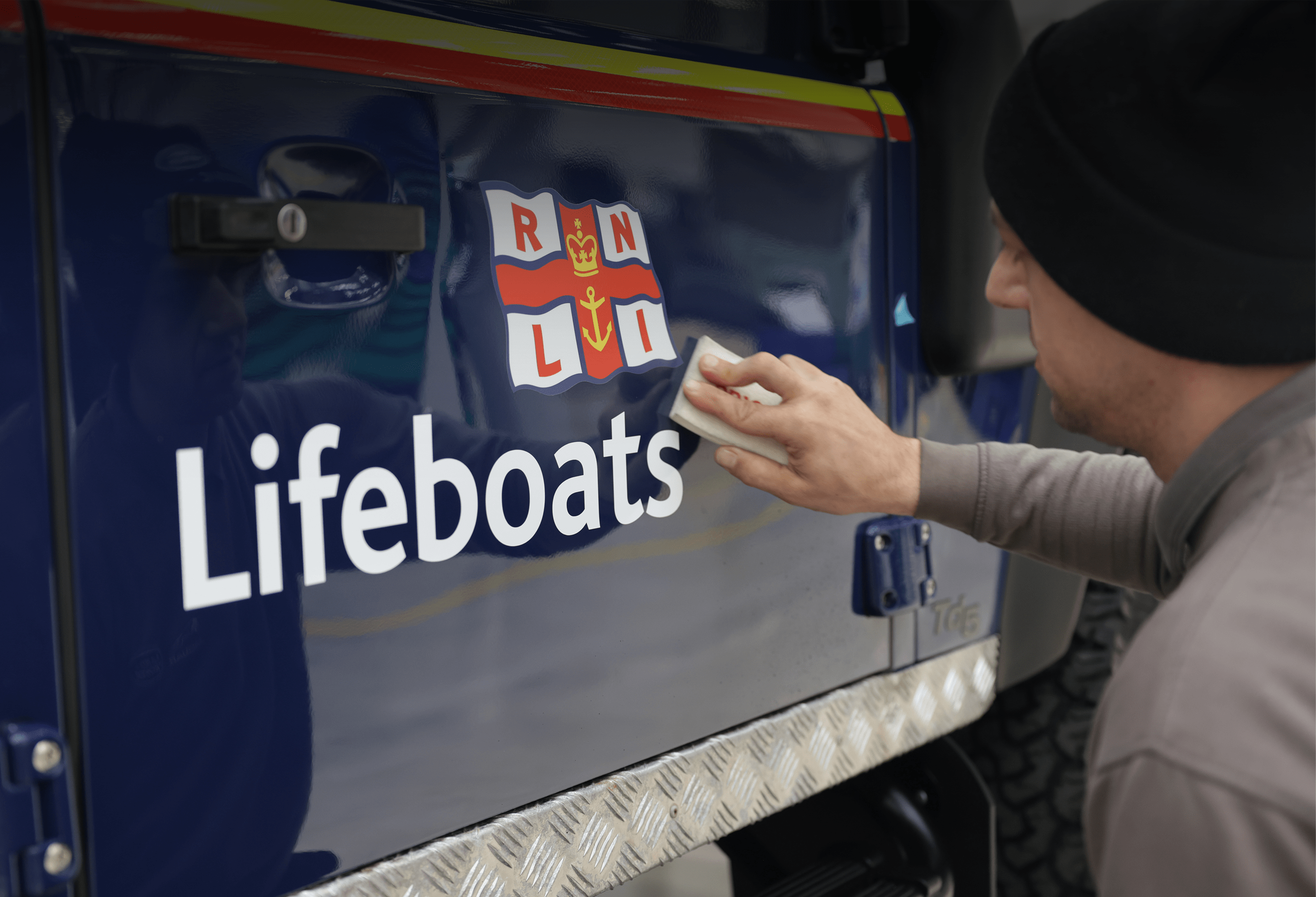 Person cleaning a vehicle marked 'Lifeboats' with RNLI emblem.