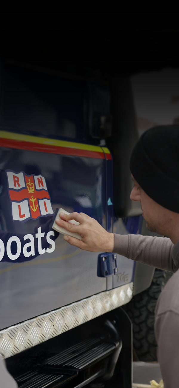 Person cleaning a vehicle marked 'Lifeboats' with RNLI emblem.