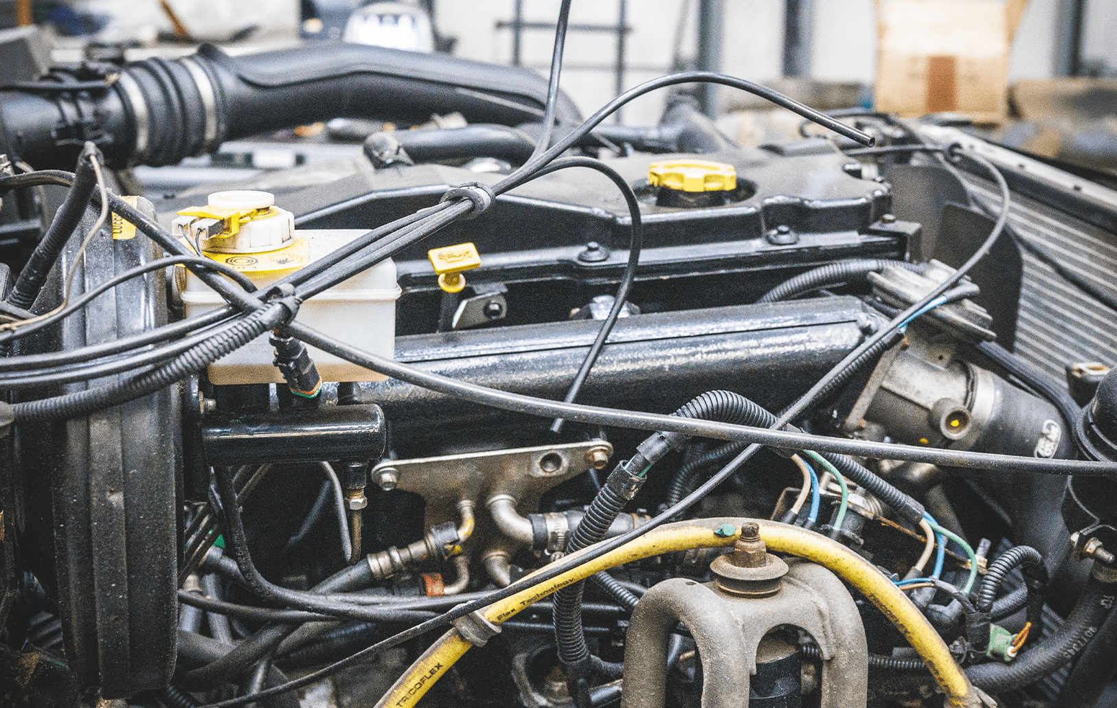 Close-up of engine compartment with hoses, wires, and yellow fluid caps.