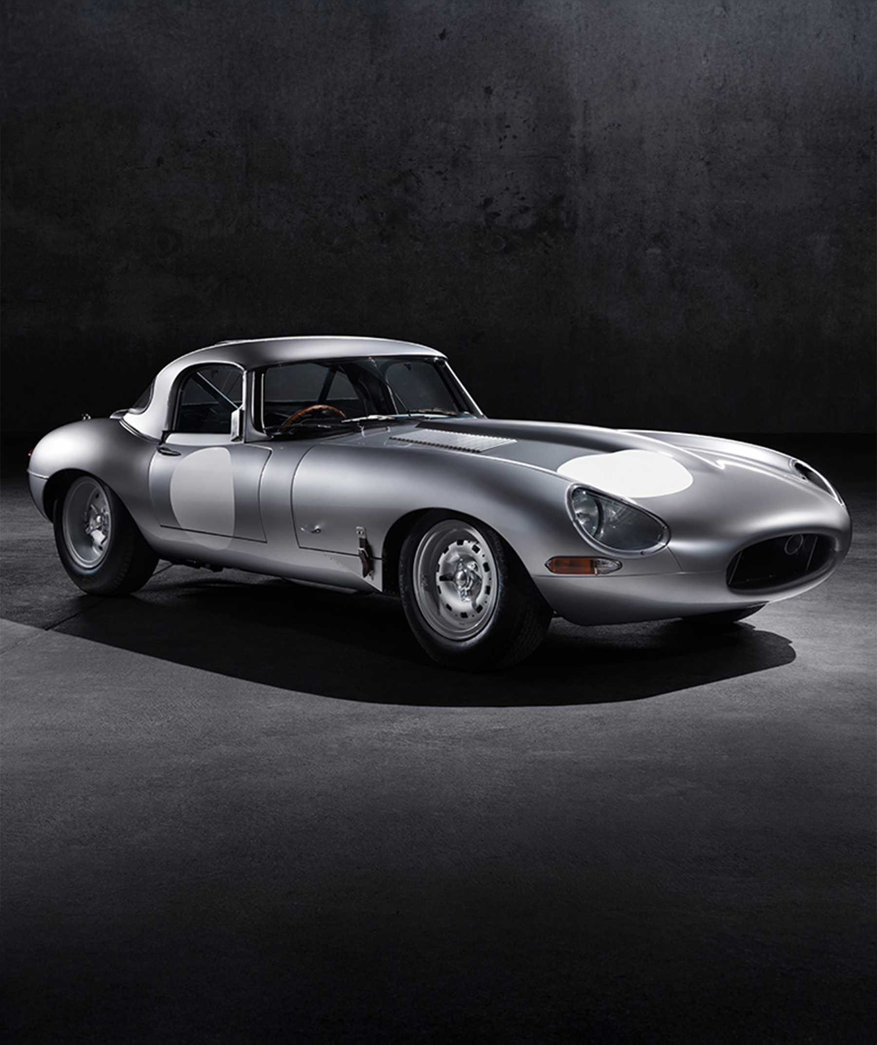 Classic silver E-Type with hardtop and round headlights.