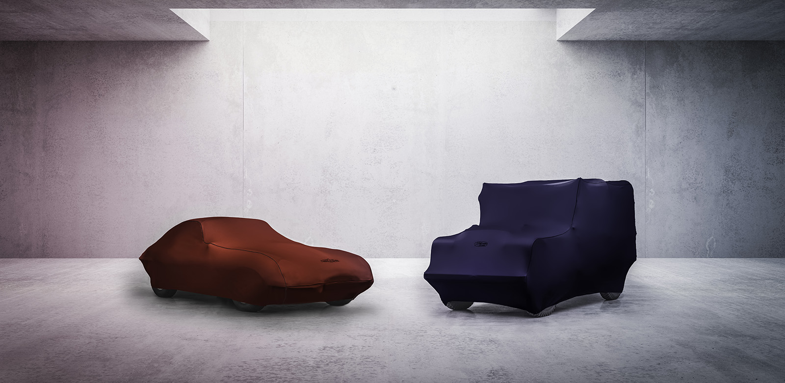 Classic Jaguar and Land Rover covered with fabric car cover in minimalist concrete room.
